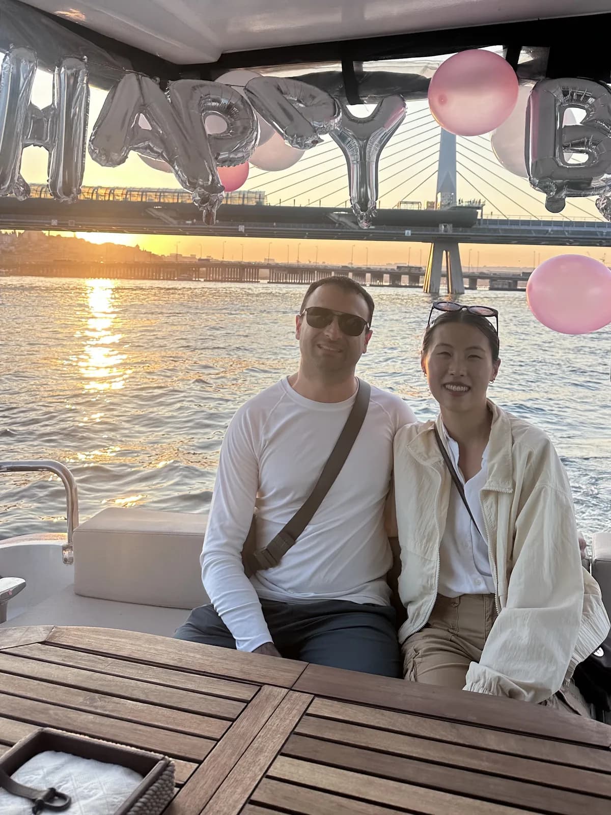 Two guests under Happy Birthday balloons on a private yacht, Golden Horn Metro Bridge at sunset