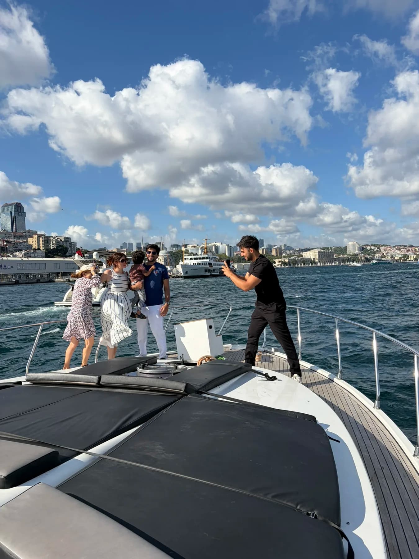 Boğaz turunda aile — anne, baba ve iki çocuk teknenin güvertesinde köprü manzarasına bakıyor