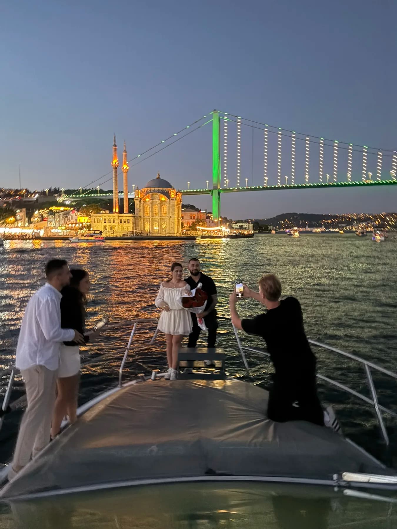 Boğaz'da gün batımı yatında dekorlu evlilik teklifi sahnesi — gül yaprakları ve mum ışığı