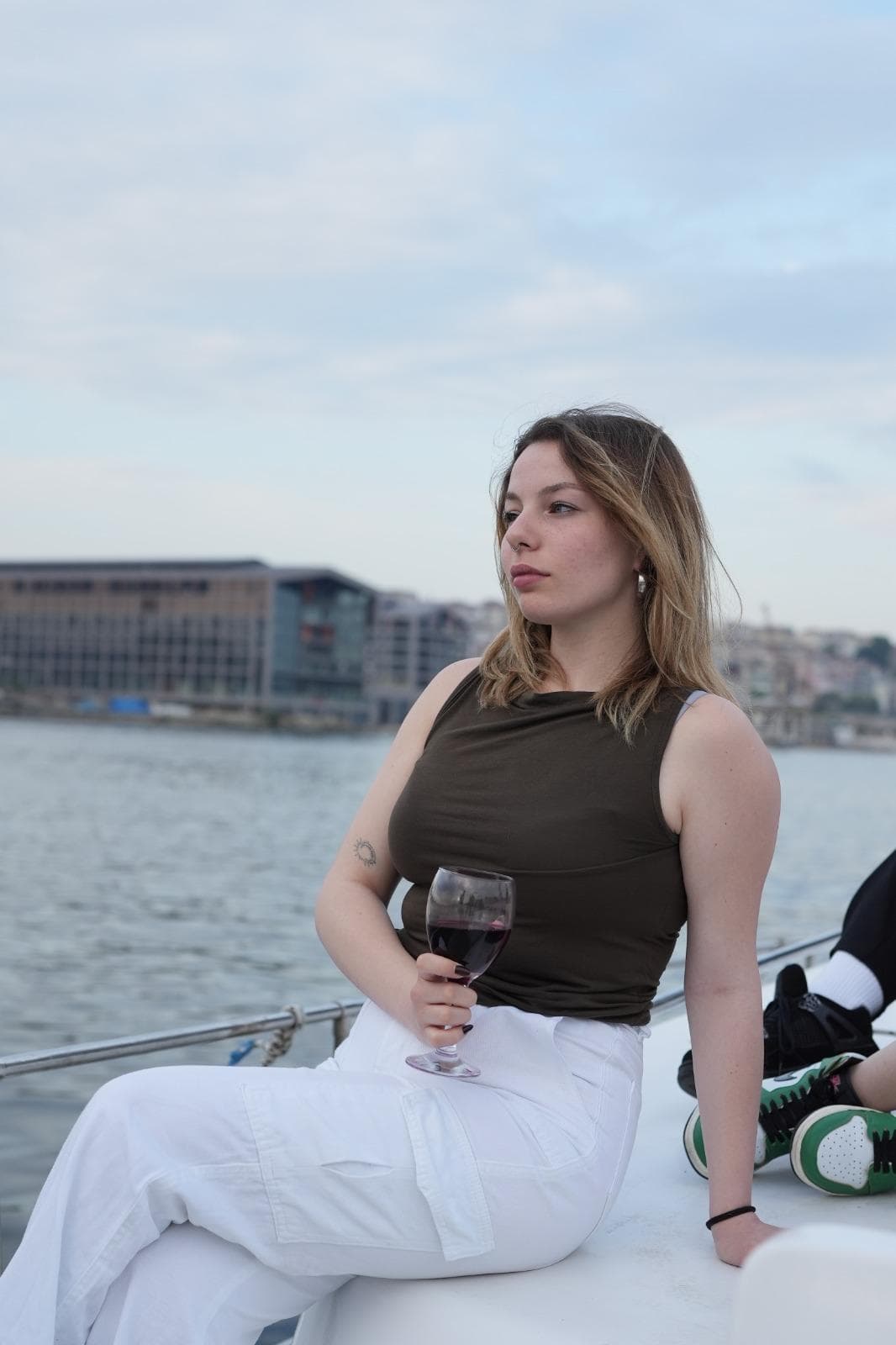Person booking a Bosphorus cruise on a smartphone with the Galata Bridge and Golden Horn visible through the window